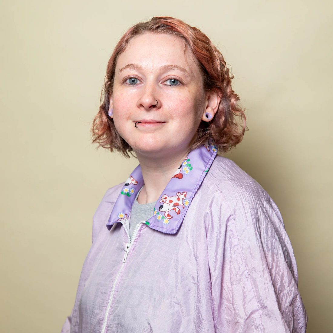 Woman with short reddish hair in purple jacket smiling
